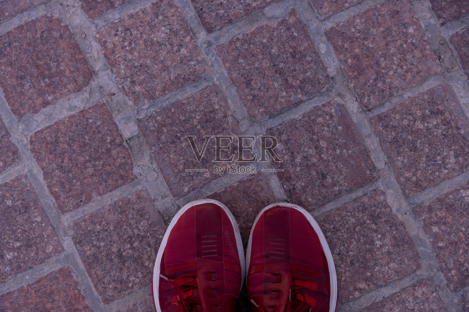 一双红鞋站在砖地板上。鞋子是图像中唯一可见的东西照片摄影图片