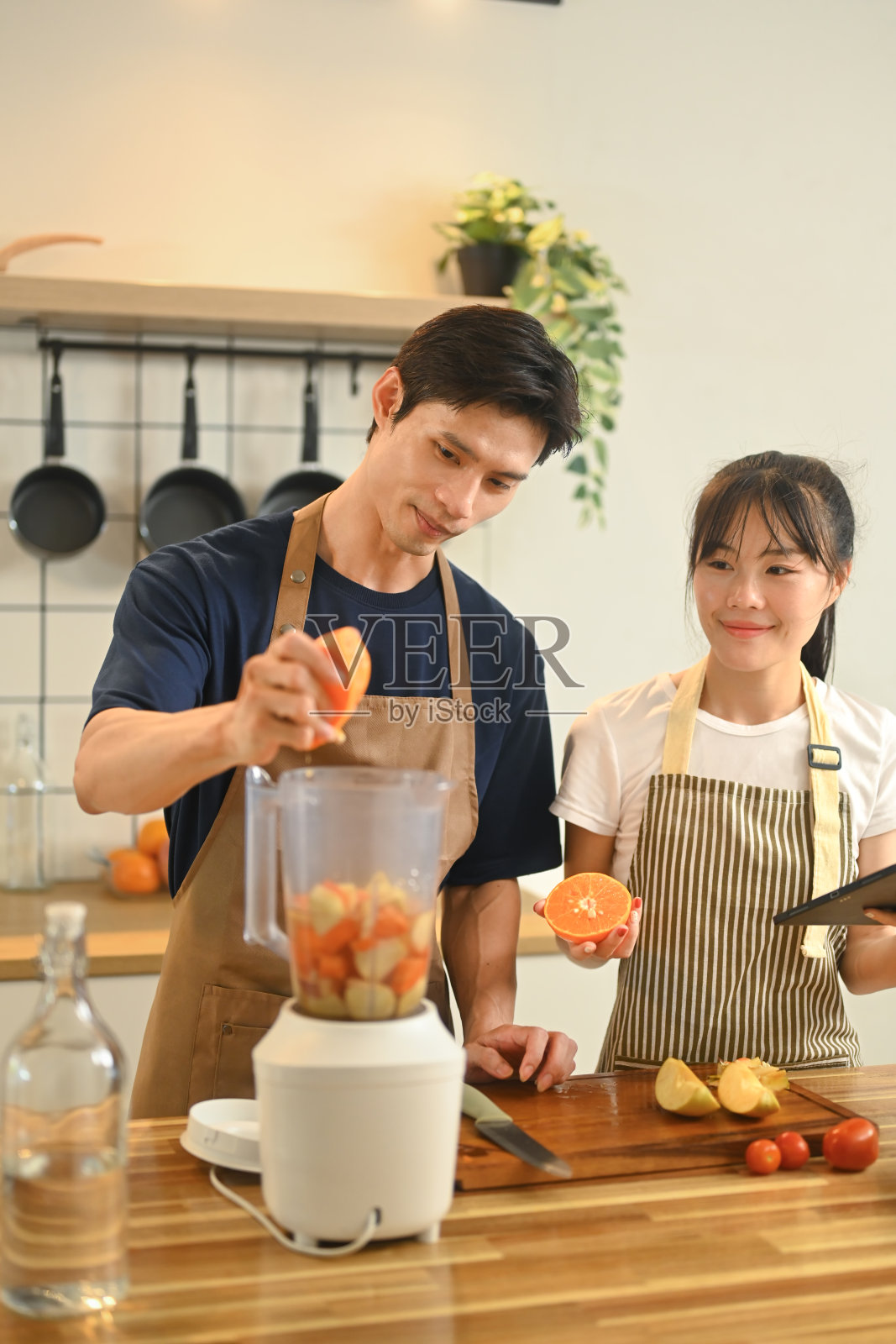 年轻夫妇在他们的现代厨房里用五颜六色的水果混合制作健康的冰沙照片摄影图片