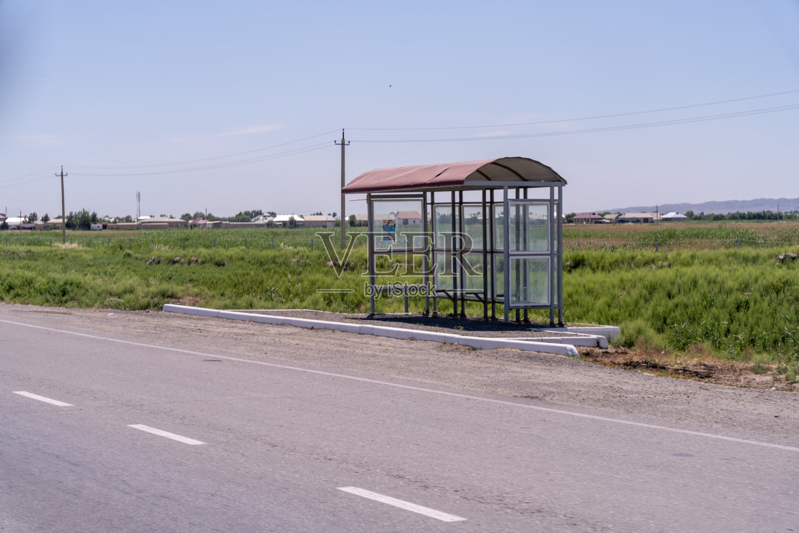 一个公共汽车站坐落在一条有很多草的路上照片摄影图片