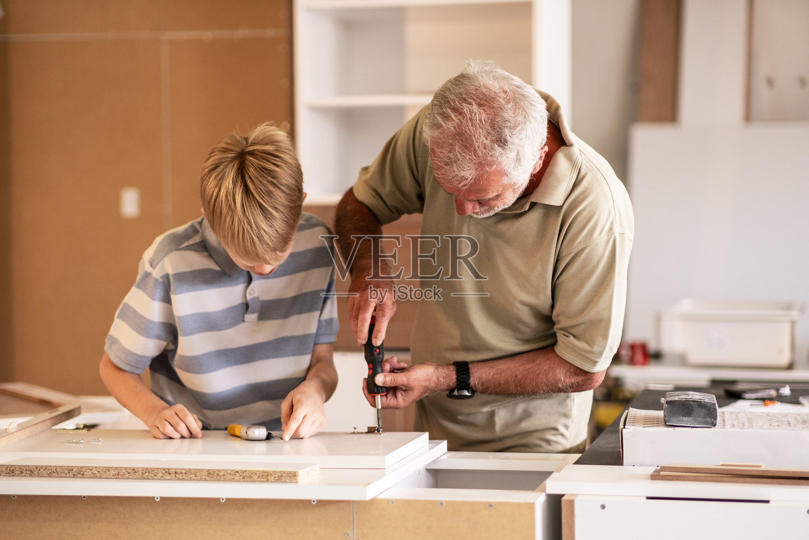 一位祖父在他的木匠作坊里教他的孙子如何修理家具。照片摄影图片