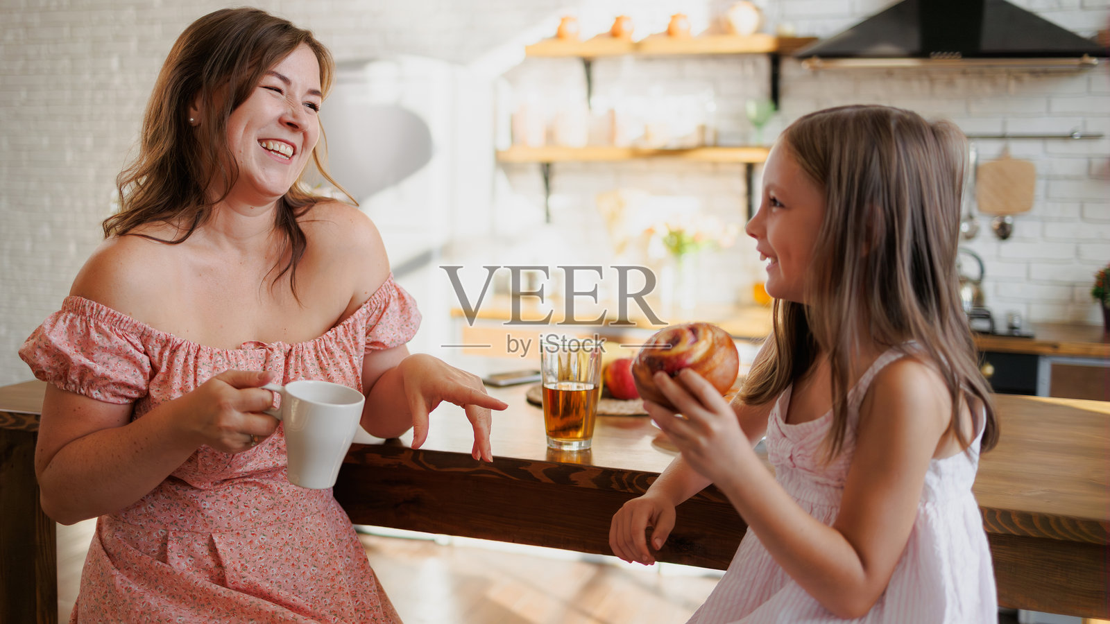 母亲和女儿在家里吃早餐时微笑着交谈照片摄影图片