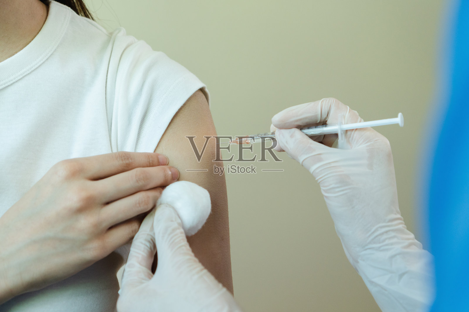 女医生戴口罩，手持注射器为病人注射疫苗，以作保护。在COVID-19爆发期间。医生在流行病期间给病人接种疫苗。照片摄影图片