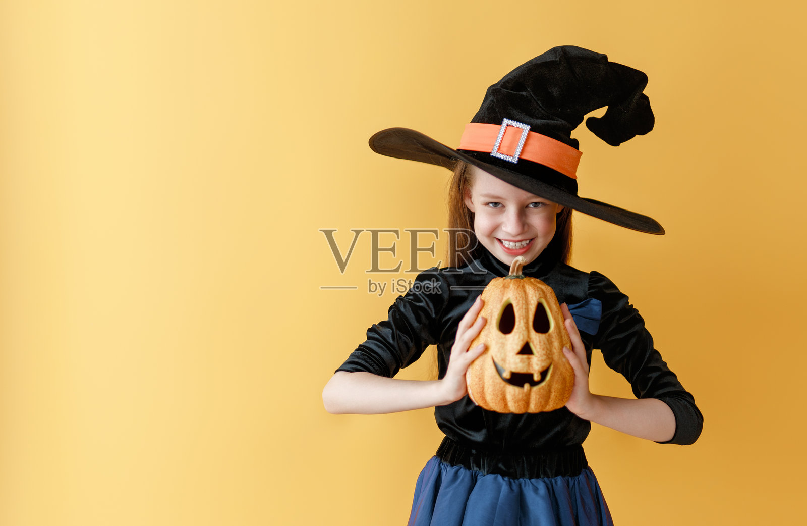 穿着女巫服装拿着万圣节南瓜的女孩照片摄影图片