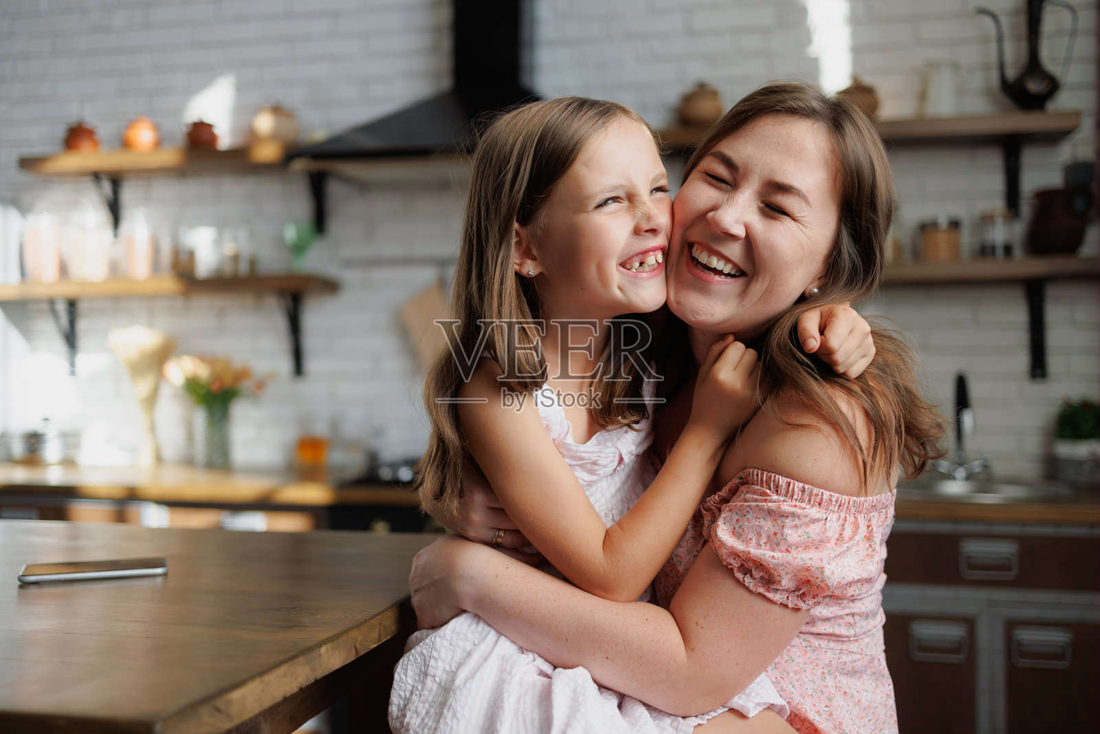 穿着背心裙的女儿微笑着在家里拥抱母亲照片摄影图片