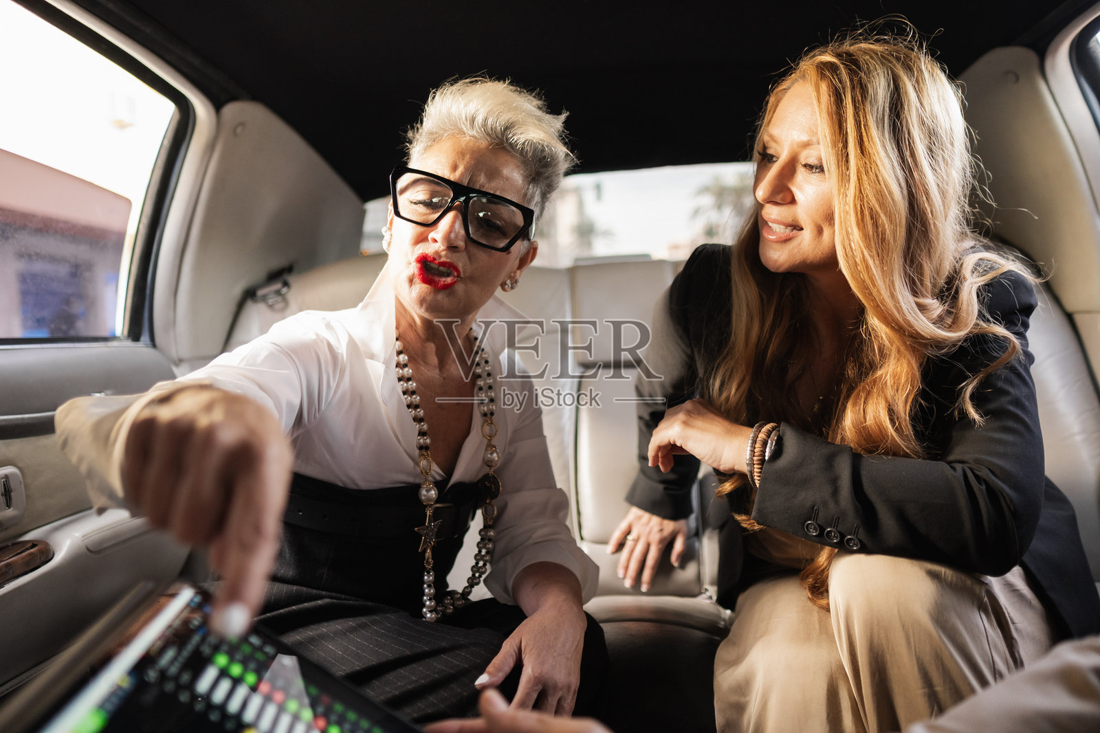 女商人在豪华轿车后座上讨论工作照片摄影图片