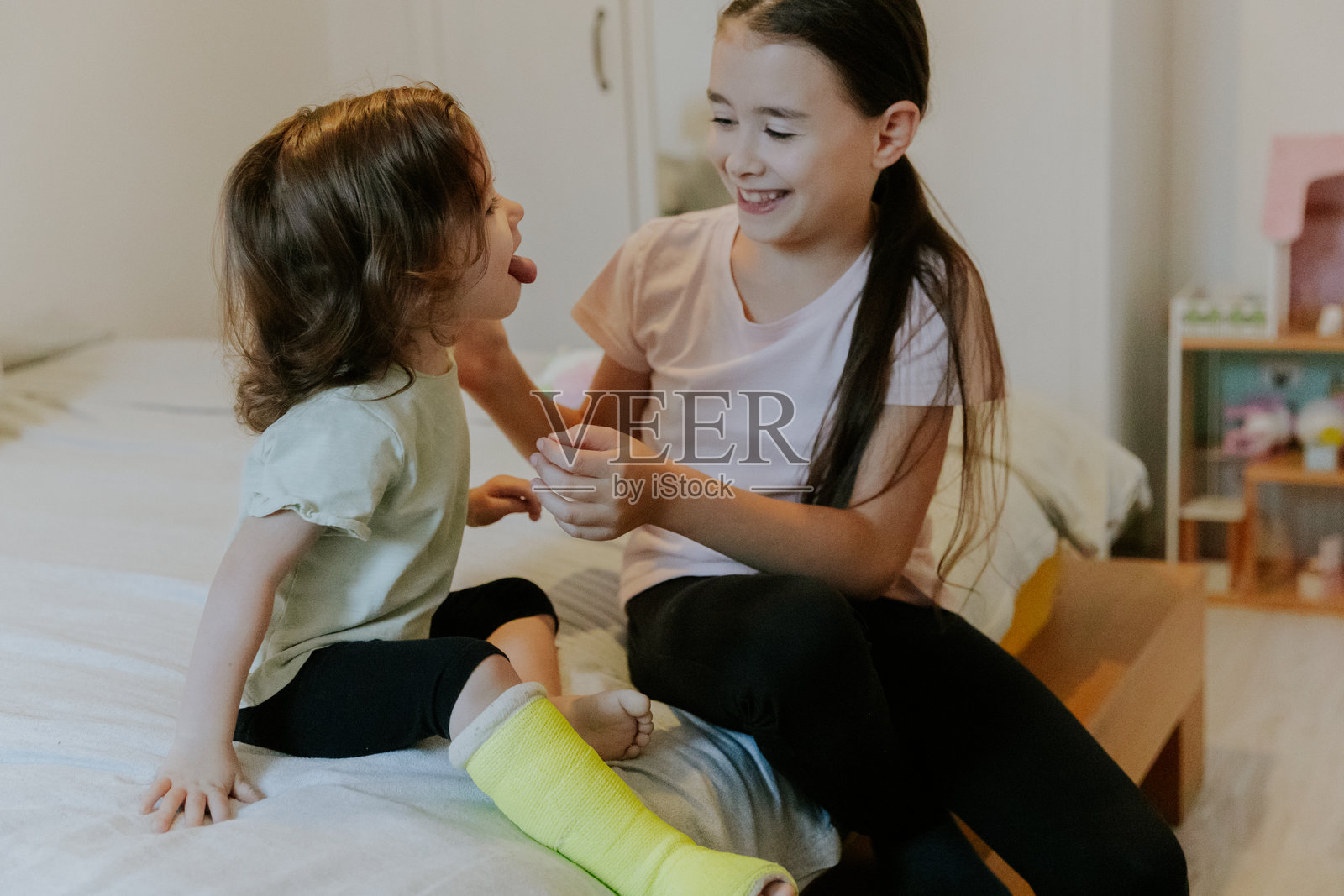 两个女孩早上坐在床上鬼混。照片摄影图片