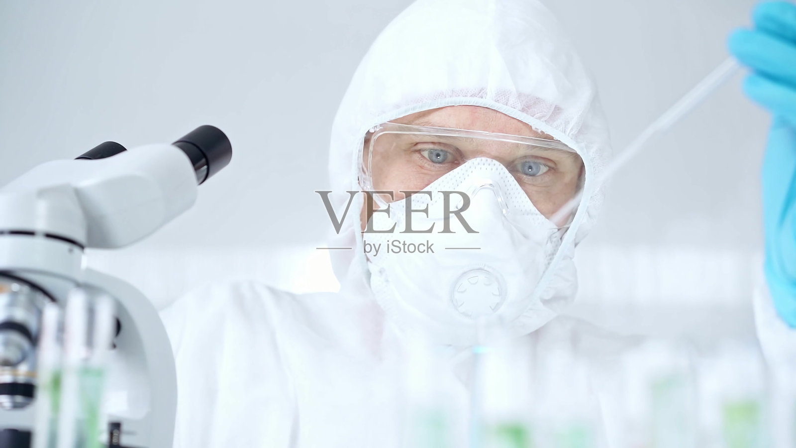 在实验室环境中，穿着防护装备的专业科学家正在使用移液器和检查试管照片摄影图片
