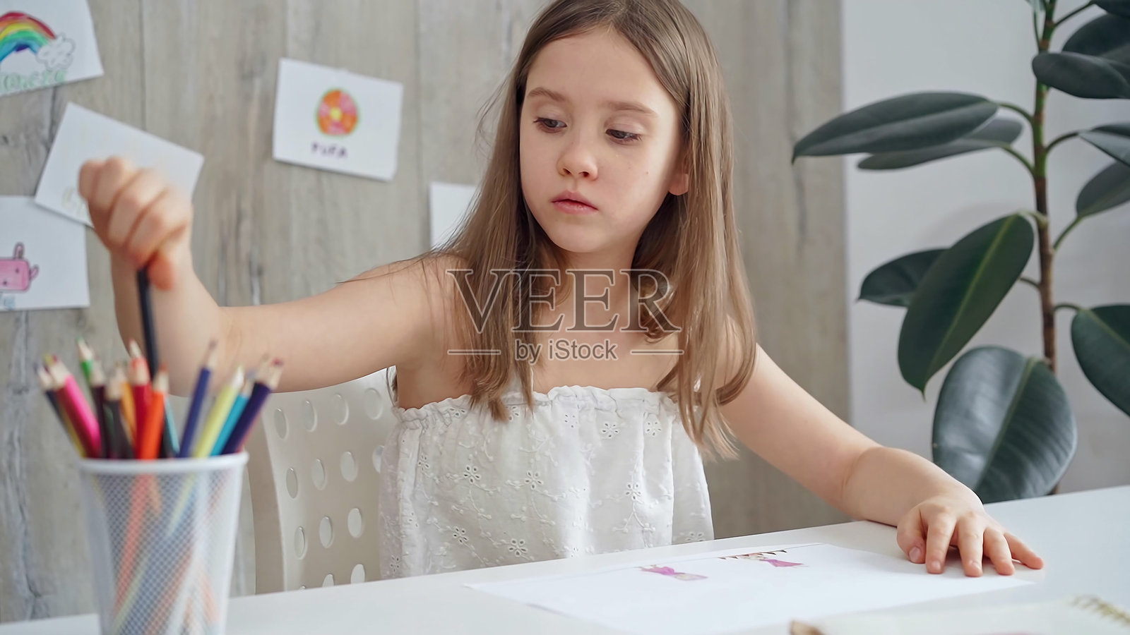 小女孩正在挑选彩色铅笔，并从一组彩色铅笔中挑选一支铅笔参加创意活动照片摄影图片