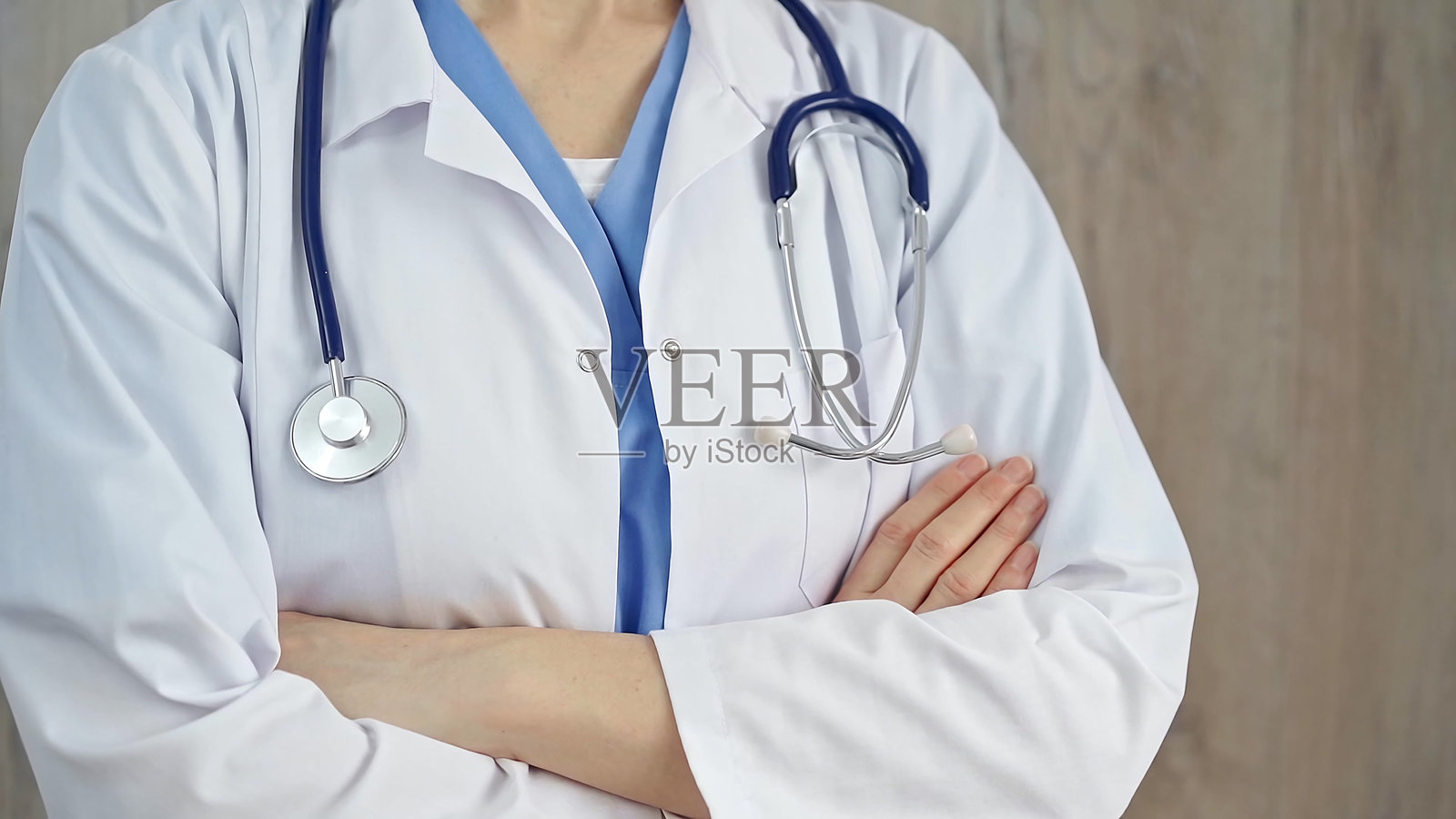 带听诊器的自信医疗保健专业人员。一位身着白大褂双臂交叉的医生的特写。医学的概念照片摄影图片