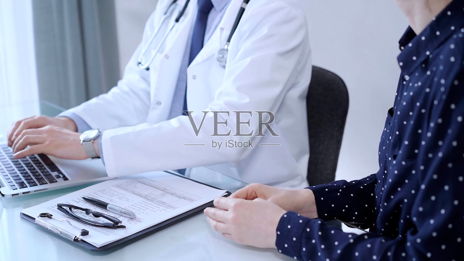 体检后，医生和病人在诊所里交谈。一位男医生正在用笔记本电脑与一位资深女性讨论检查结果。医学的概念照片摄影图片