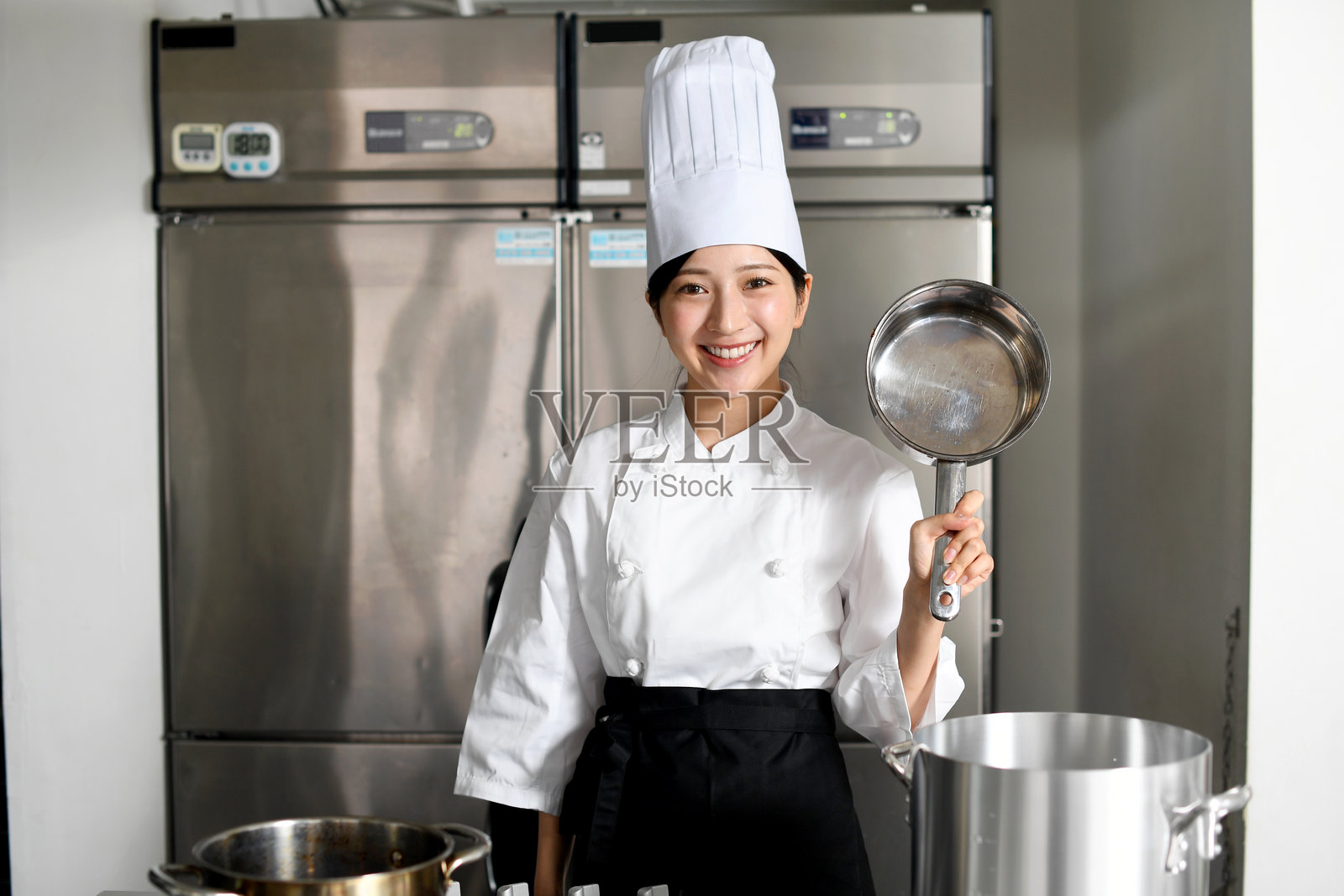 亚洲年轻女厨师在厨房用大锅做饭照片摄影图片