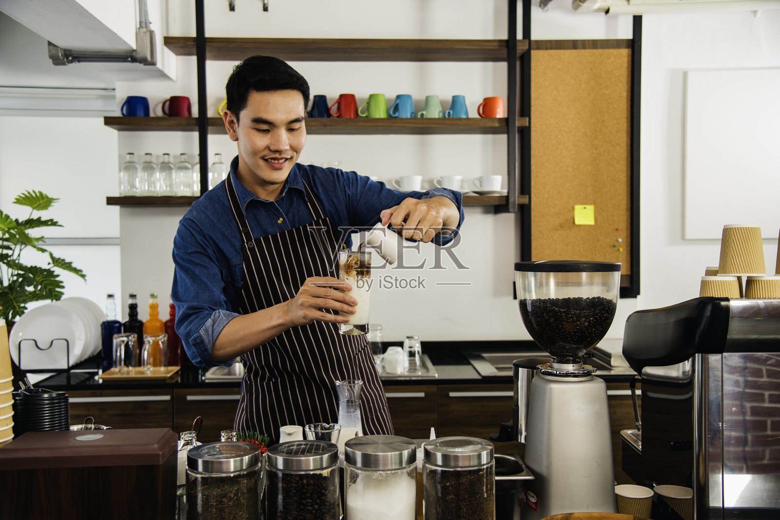 咖啡师用咖啡机的热杯制作浓缩咖啡。意大利咖啡馆里的牛奶卡布奇诺。近距离的咖啡师用机器为顾客自助餐厅制作棕色拉花照片摄影图片