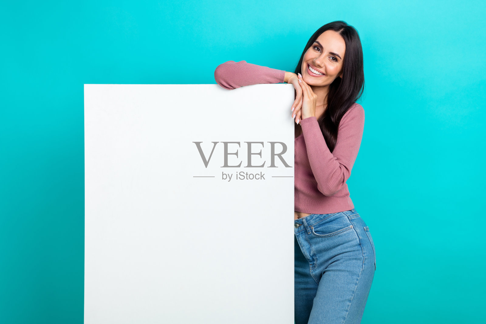 可爱的积极女孩的肖像，露齿微笑，展示了绿松石色背景上的空白和空白照片摄影图片