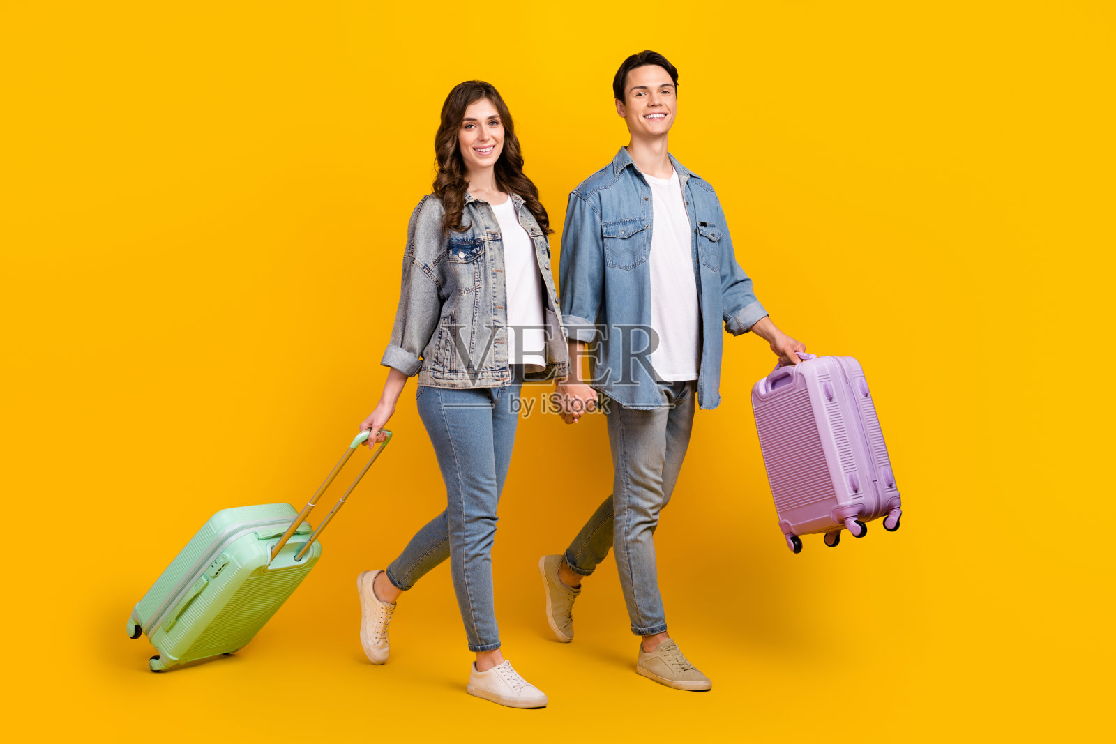 两个积极的伙伴的全尺寸肖像抱着手臂手提箱行走孤立的黄色背景照片摄影图片