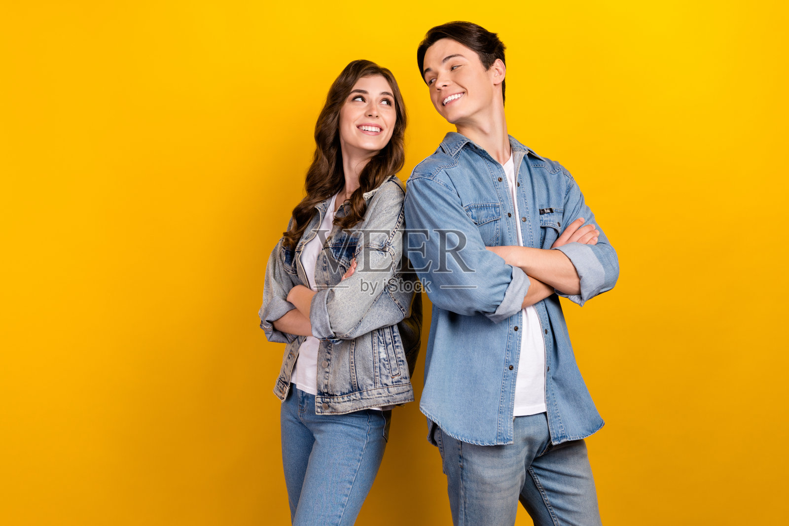 在黄色的背景上，两个欢快的人抱臂相望，露出灿烂的笑容照片摄影图片