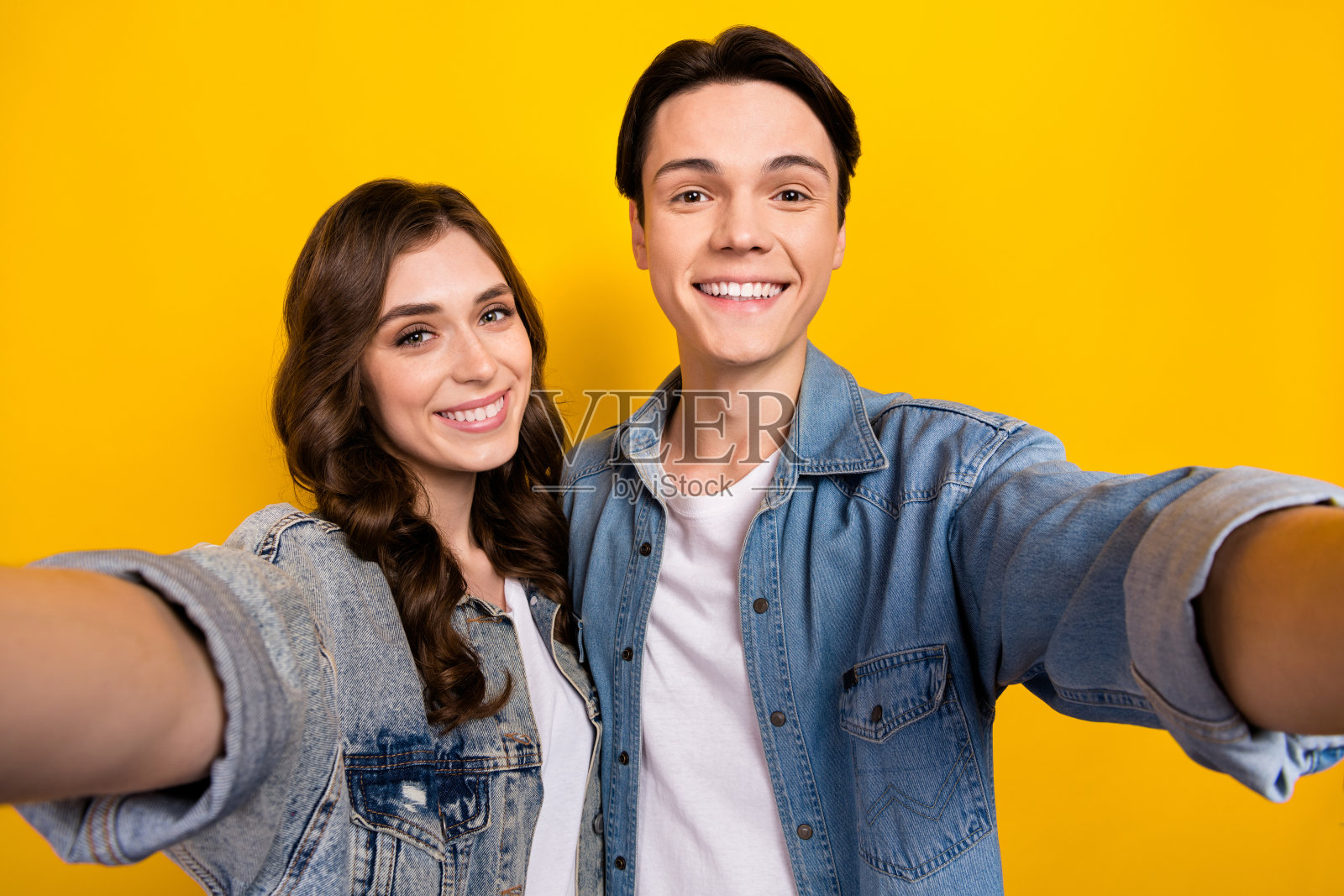 两个积极友好的伴侣的肖像，牙齿微笑，自拍记录视频孤立在黄色背景照片摄影图片