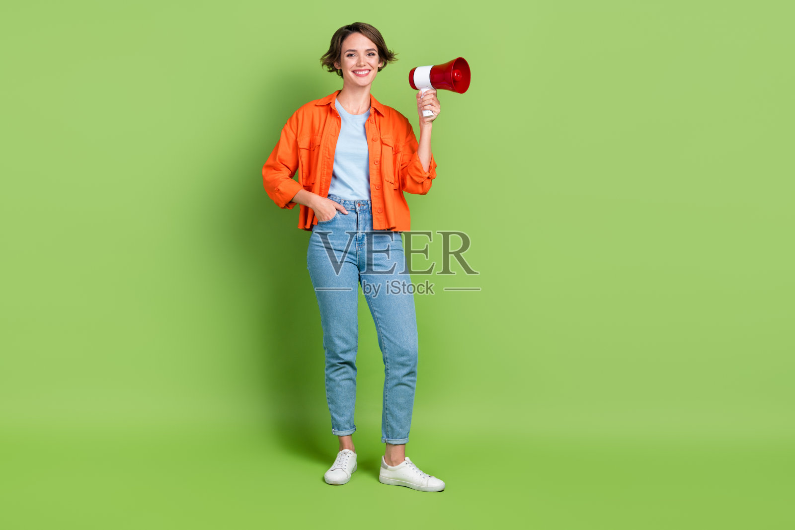 全身照片可爱闪亮的女士穿着牛仔裤衬衫拿着一个空白的空间孤立的绿色背景照片摄影图片