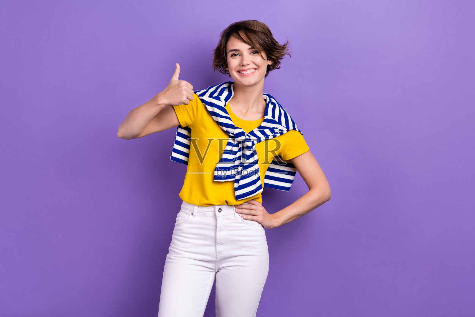 照片中，自信甜美的女士穿着系着领带的套头衫，微笑着竖起大拇指，背景是孤立的紫罗兰色照片摄影图片