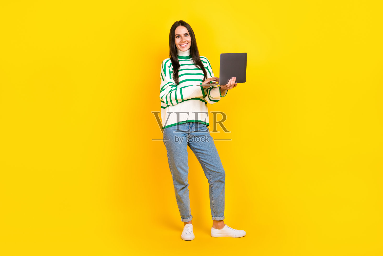 可爱的积极的女士穿着时尚的衣服，呈现新奇的设备小工具孤立在黄色背景的全身照片照片摄影图片