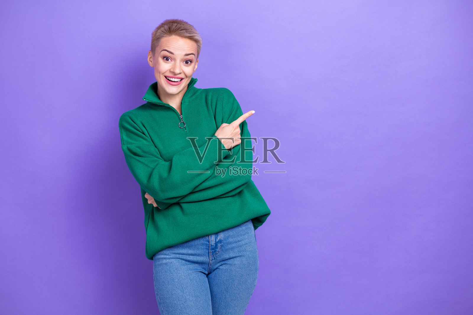 照片中兴奋的女孩穿着绿色的拉链羊毛夹克，显示手指模型，疯狂的季节购物销售孤立在紫色的背景照片摄影图片