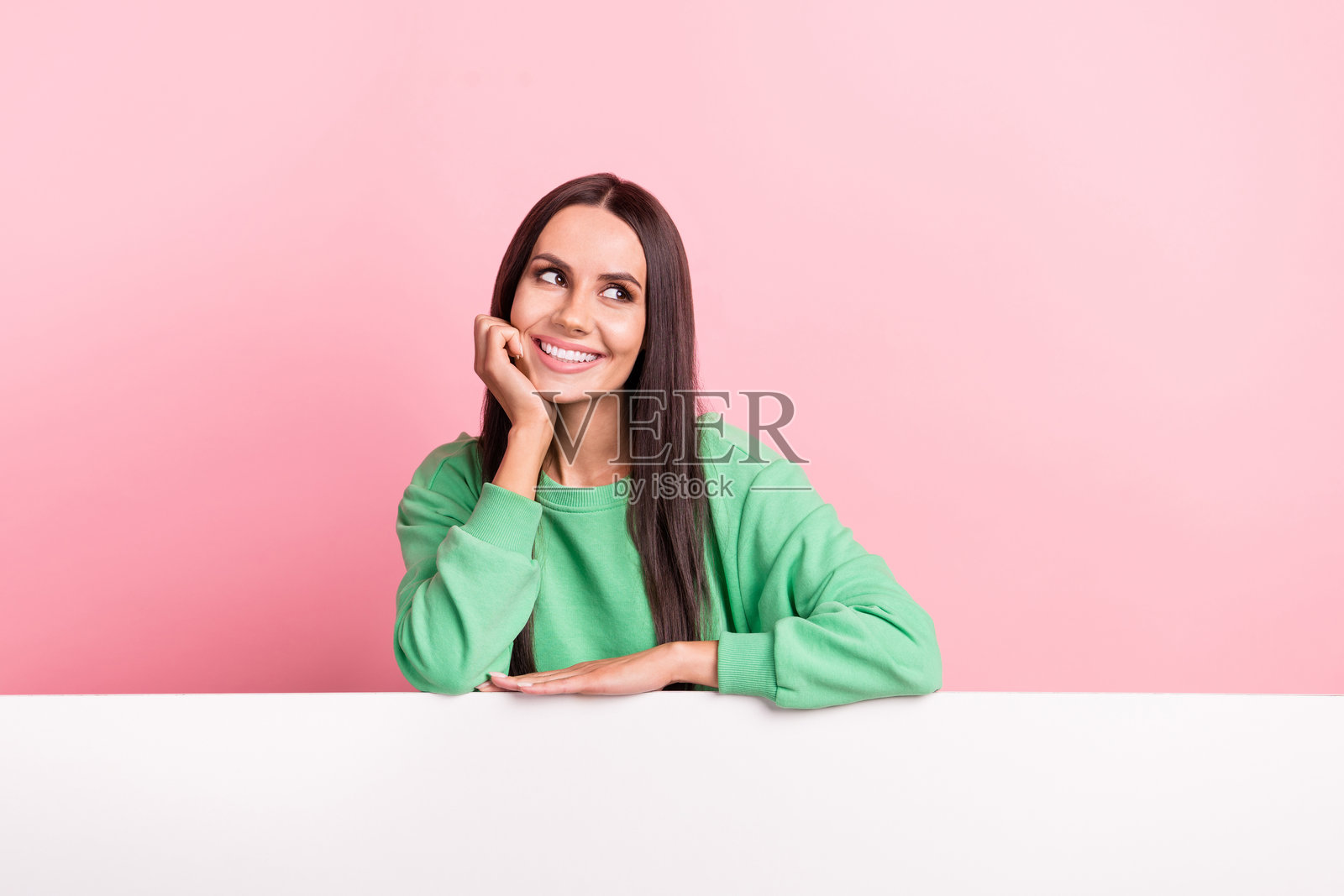 肖像正面满意可爱的女孩直发穿绿色套头衫看空空间折扣孤立在粉红色的背景照片摄影图片