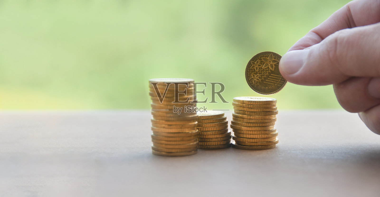 手把硬币放在一个叠硬币上。财富和复制空间的概念照片摄影图片