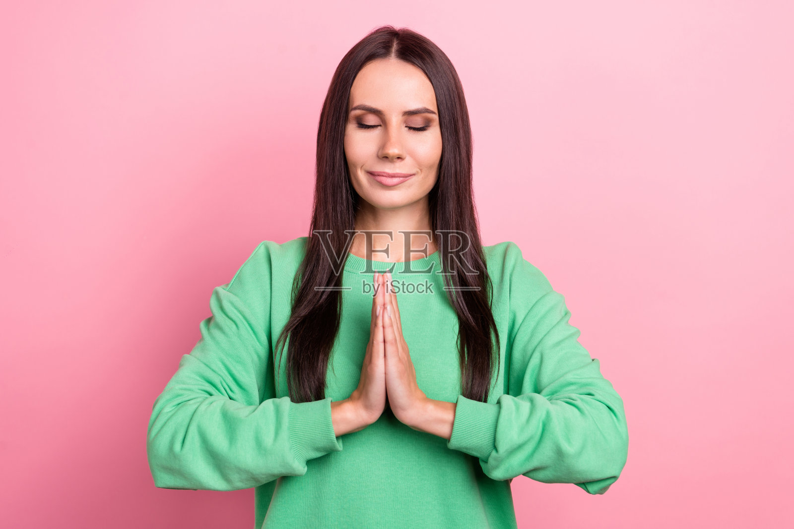 年轻的照片闭上眼睛迷人的拉丁女士穿着绿色的衬衫双手在一起体式冥想放松时间孤立在粉红色的背景照片摄影图片