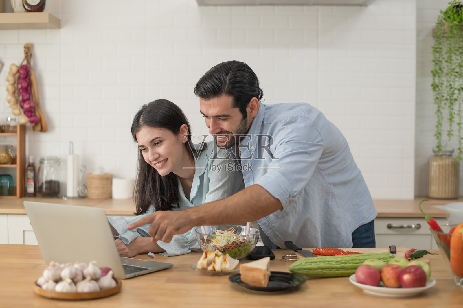 幸福的夫妇在家准备食物，年轻的夫妇在厨房柜台一起切菜照片摄影图片