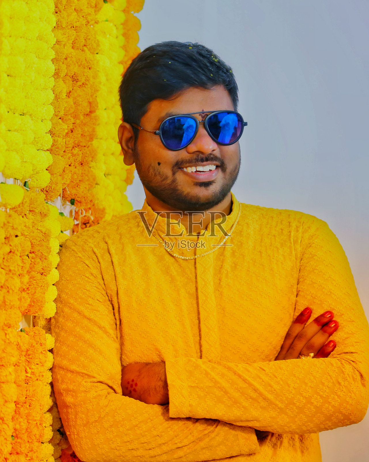 戴墨镜的年轻人站在花墙装饰前的肖像照片摄影图片