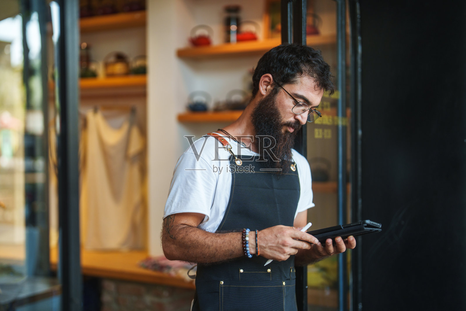 咖啡师正在咖啡厅入口处使用平板电脑。照片摄影图片