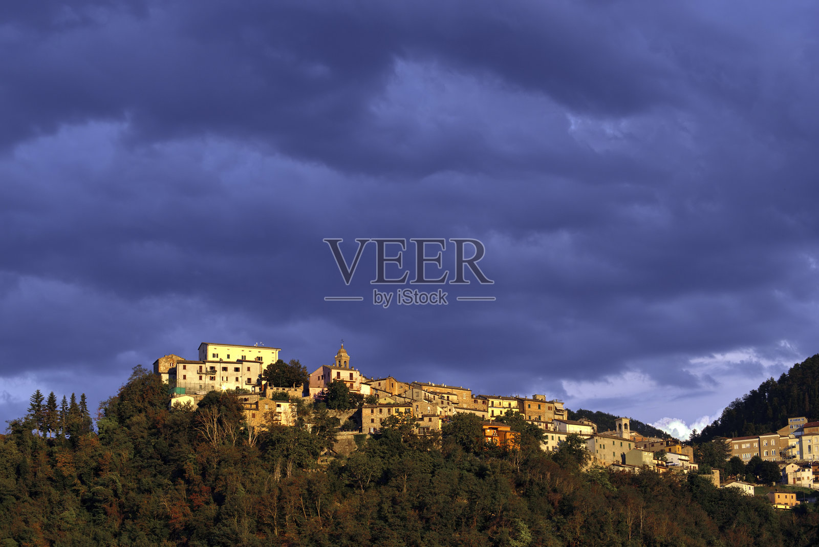 山丘上的小镇，暴风雨的天空下的黄金时刻照片摄影图片
