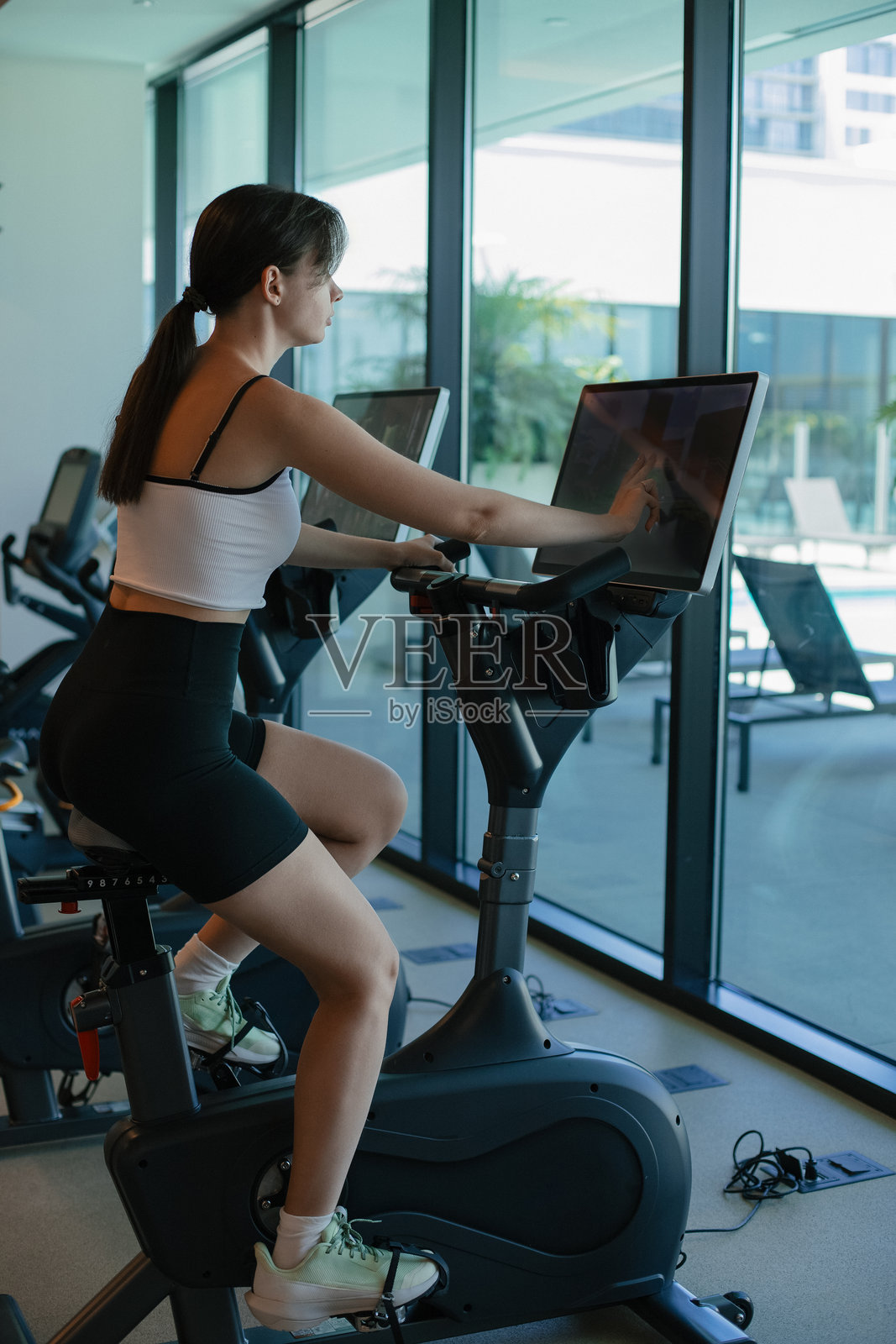 在健身房锻炼，女孩在健身房，健身自行车，运动，女孩训练，女孩健康的生活方式，保持身体的形状，健身房在美国的房子，健身房在你自己的家照片摄影图片