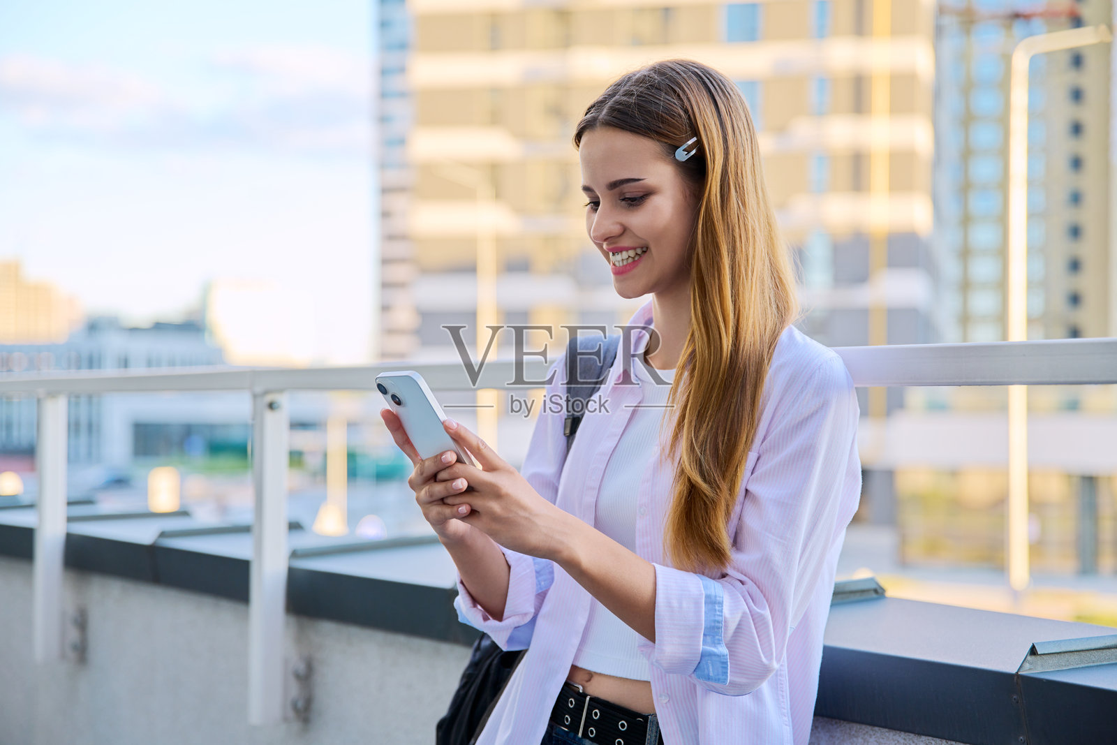 年轻女性使用智能手机，现代城市背景照片摄影图片