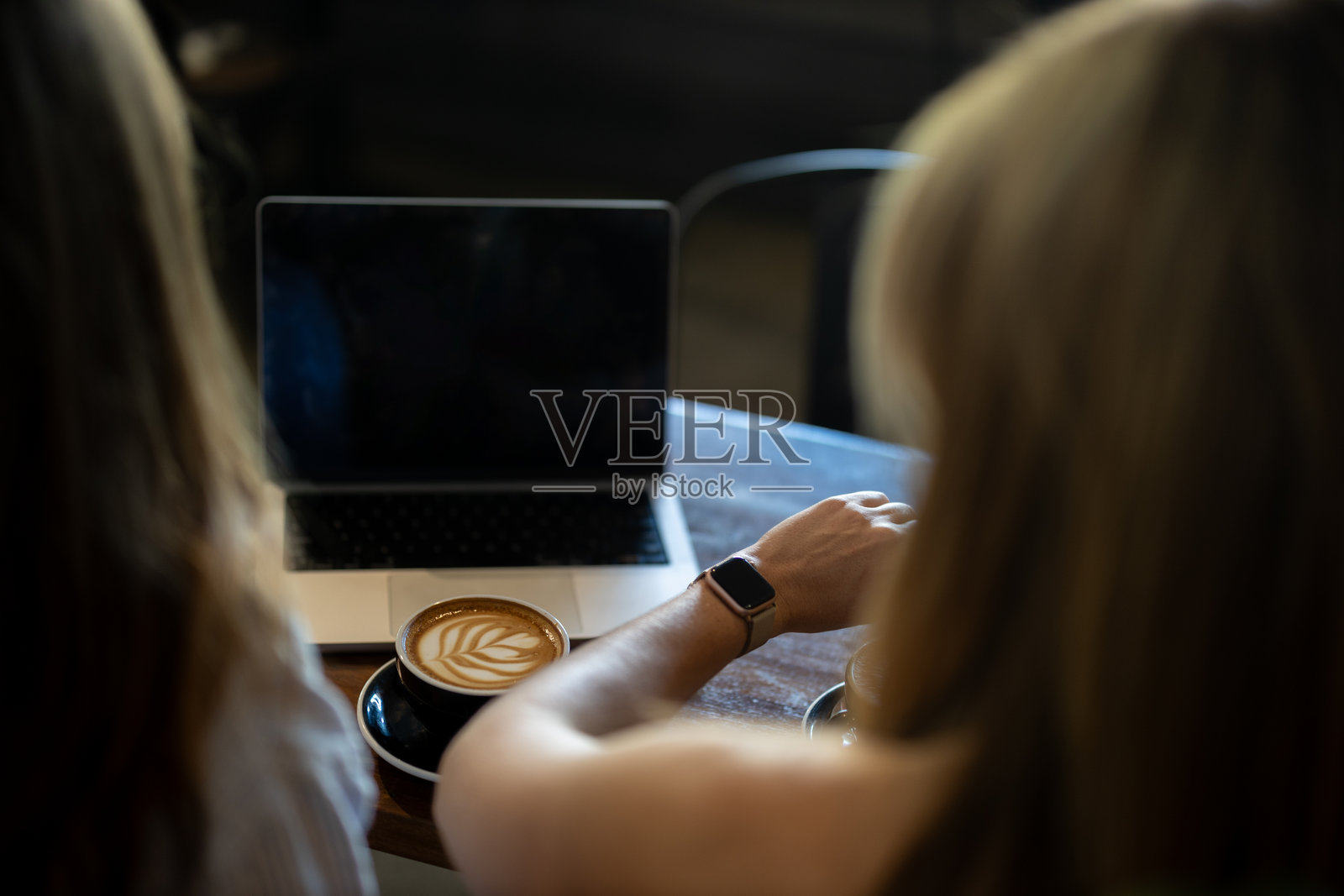 两名年轻女性在咖啡馆工作，喝着咖啡师煮的咖啡。照片摄影图片