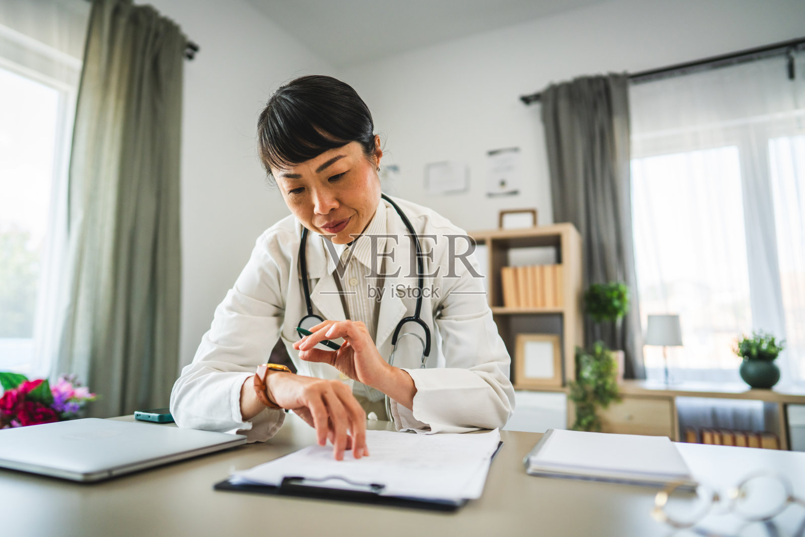 成熟的日本医生在办公室从剪贴板上读出症状照片摄影图片