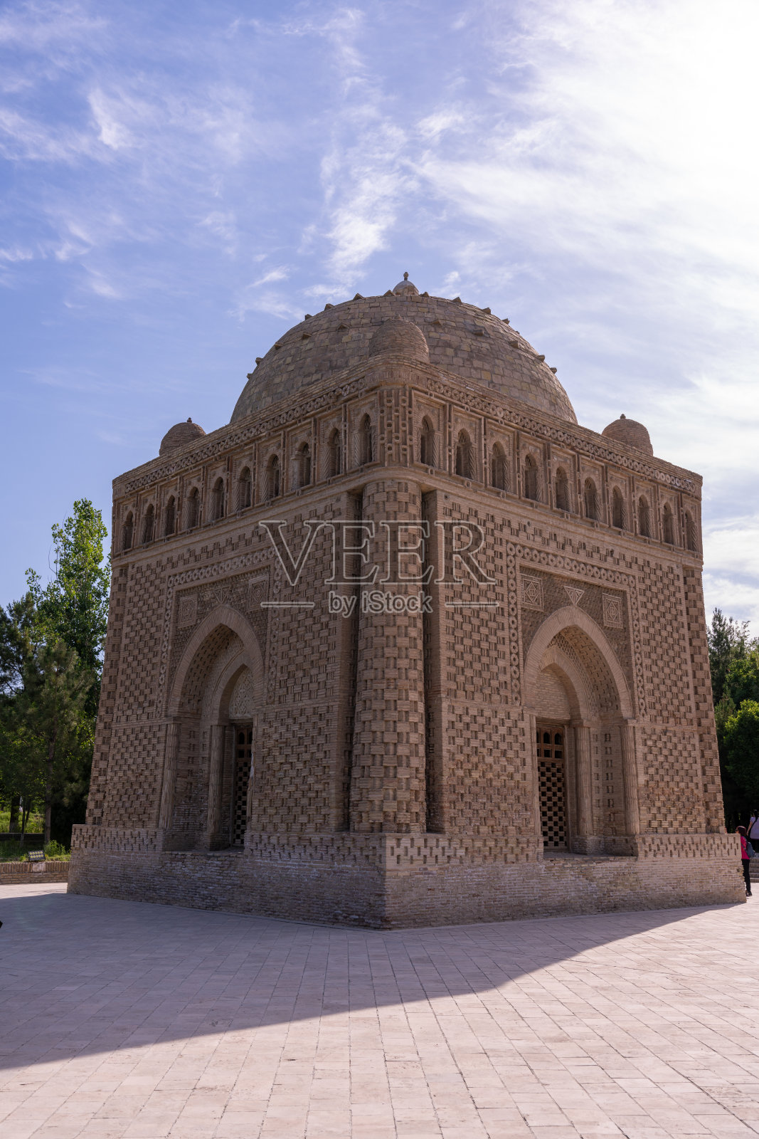 圆顶建筑顶部有圆顶的大型建筑这座建筑是棕色的，有很多拱门。天空是蓝色的，背景中有树照片摄影图片