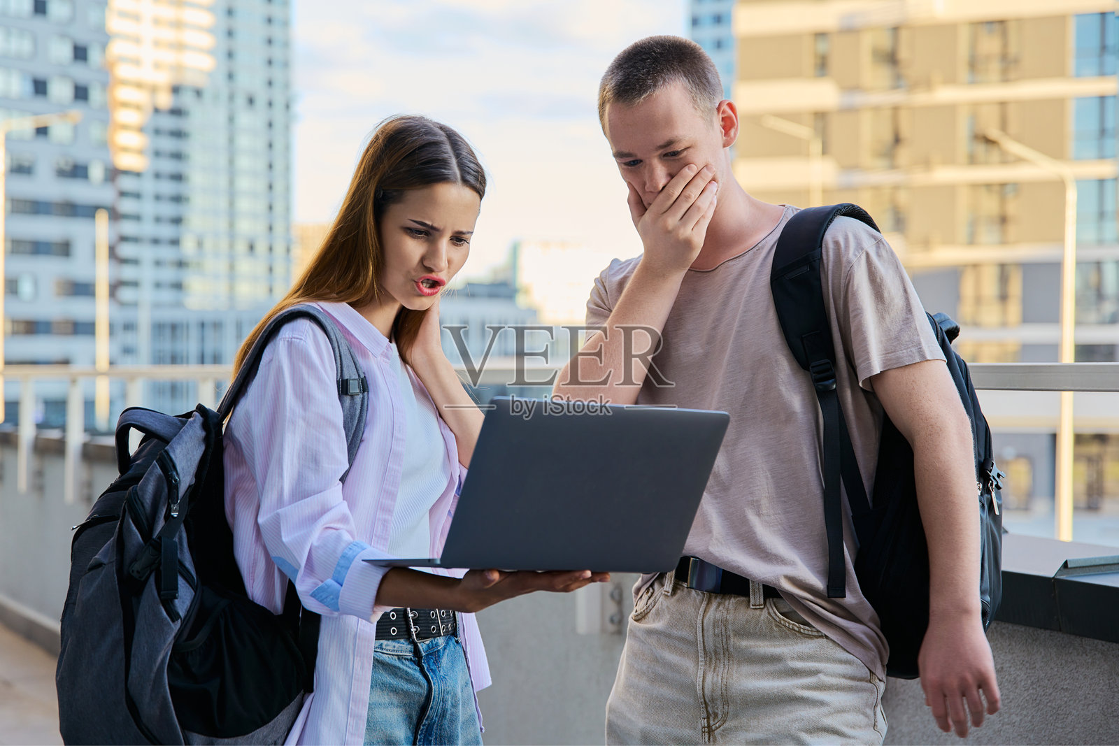 惊讶的青少年大学生看着笔记本电脑屏幕，现代城市的背景照片摄影图片