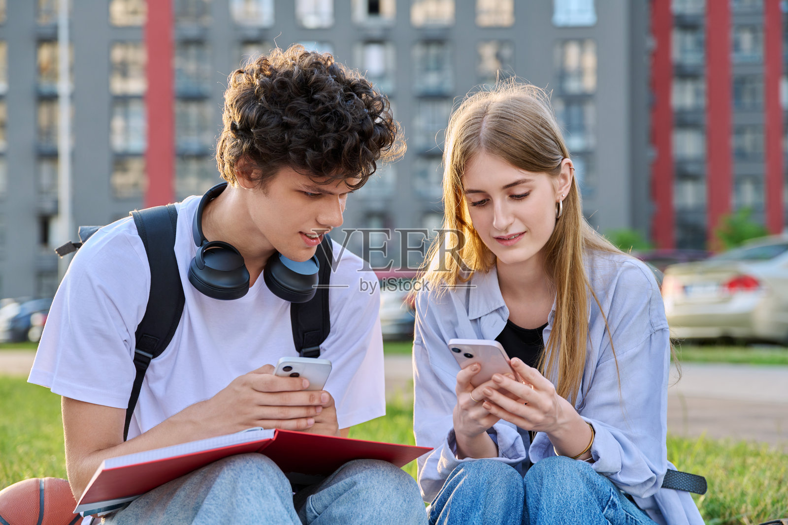 十几岁的大学生男女聊天，用智能手机，坐在户外照片摄影图片