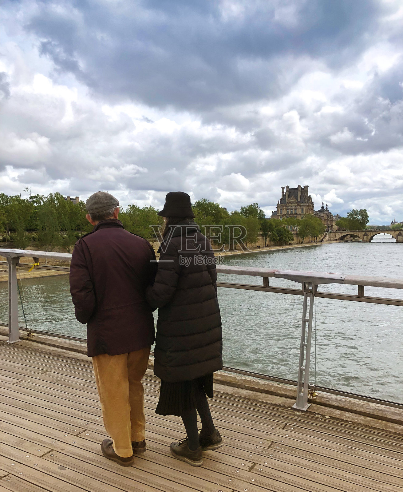 法国，巴黎:一对老年夫妇走过塞纳河照片摄影图片