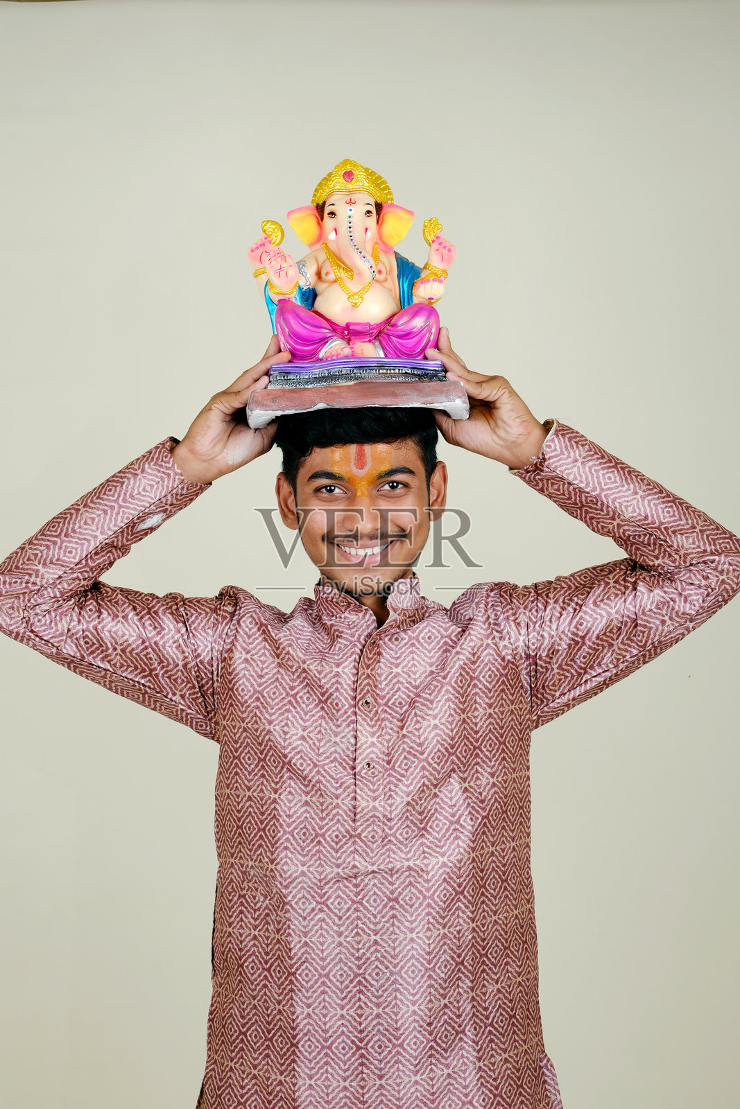 一个额头上戴着毗湿奴教头巾的印度年轻人，正在欢迎他尊敬的神——甘帕蒂。照片摄影图片