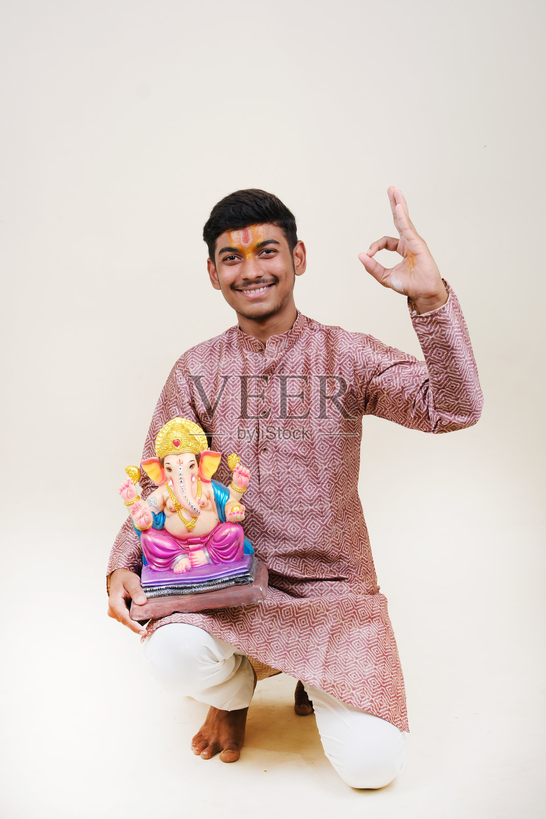 一个额头上戴着毗湿奴教头巾的印度年轻人，正在欢迎他尊敬的神——甘帕蒂。照片摄影图片