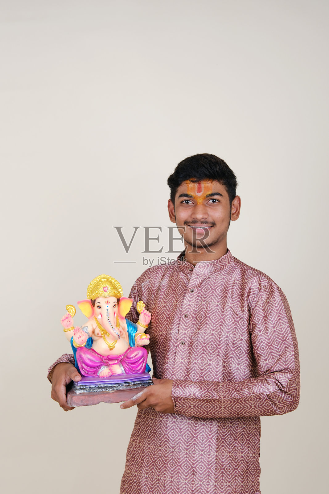 一个额头上戴着毗湿奴教头巾的印度年轻人，正在欢迎他尊敬的神——甘帕蒂。照片摄影图片