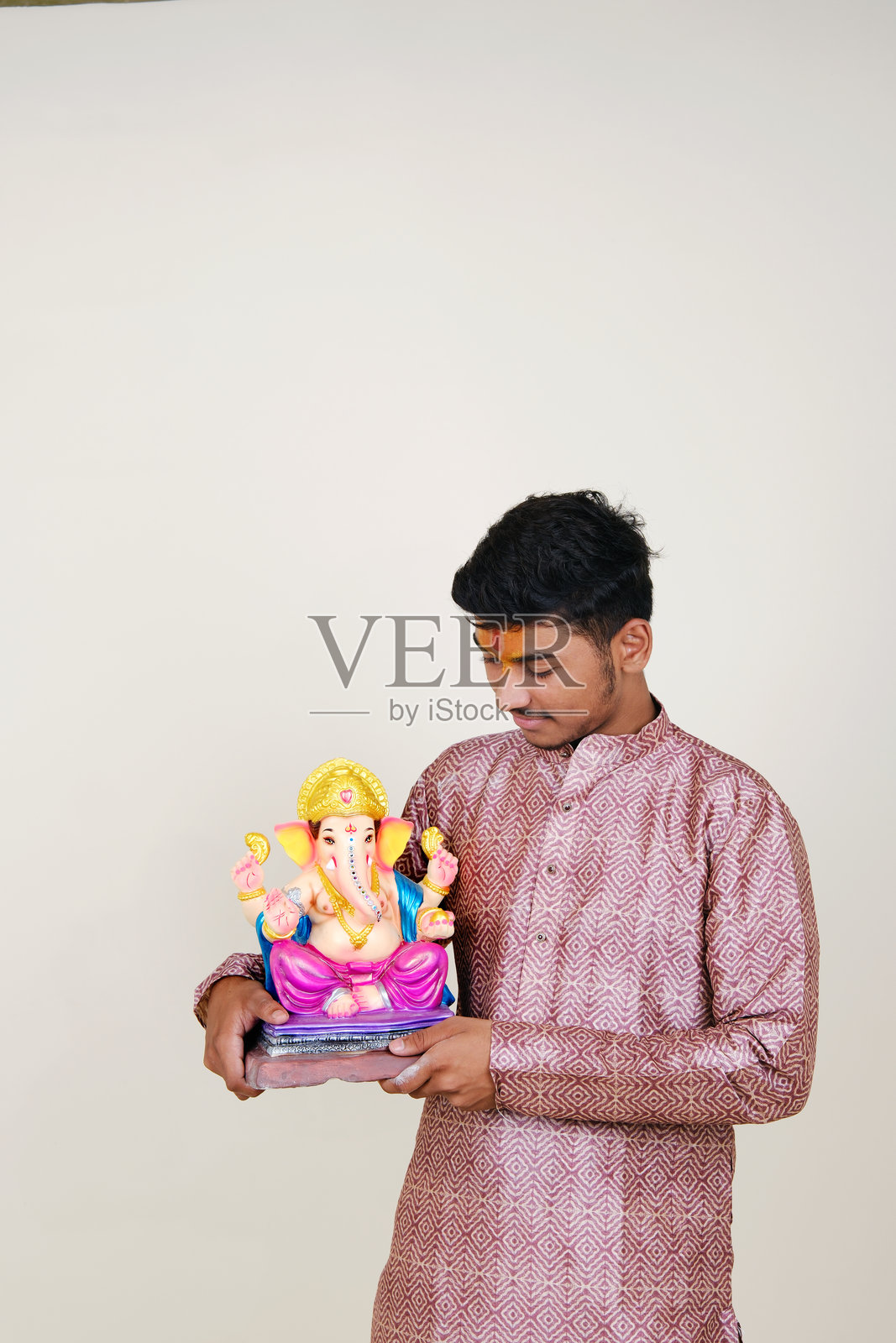 一个额头上戴着毗湿奴教头巾的印度年轻人，正在欢迎他尊敬的神——甘帕蒂。照片摄影图片