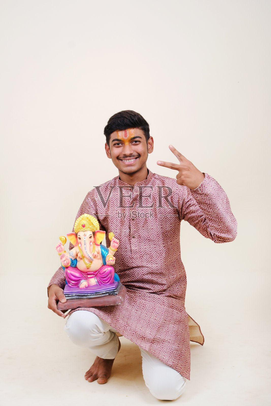 一个额头上戴着毗湿奴教头巾的印度年轻人，正在欢迎他尊敬的神——甘帕蒂。照片摄影图片