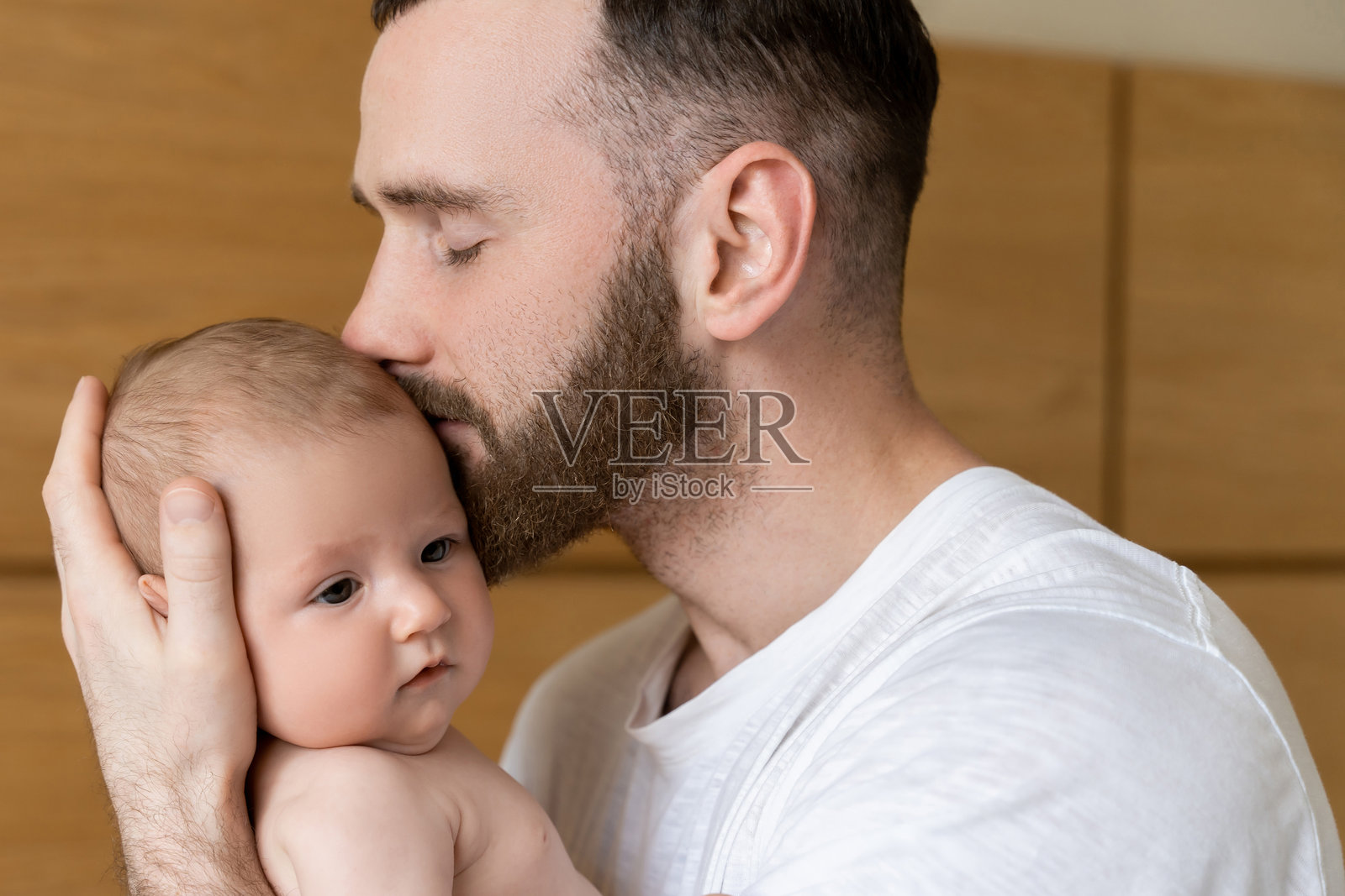 父亲独自在家照顾婴儿时亲吻新生儿照片摄影图片
