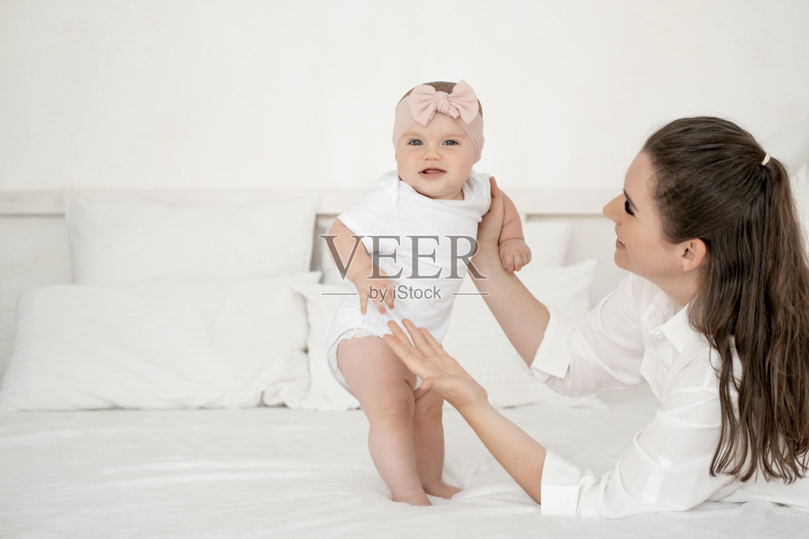 妈妈和宝宝在家里卧室的床上拥抱亲吻，父母的爱和关怀，快乐的母亲，妈妈抱着宝宝，文字的空间照片摄影图片