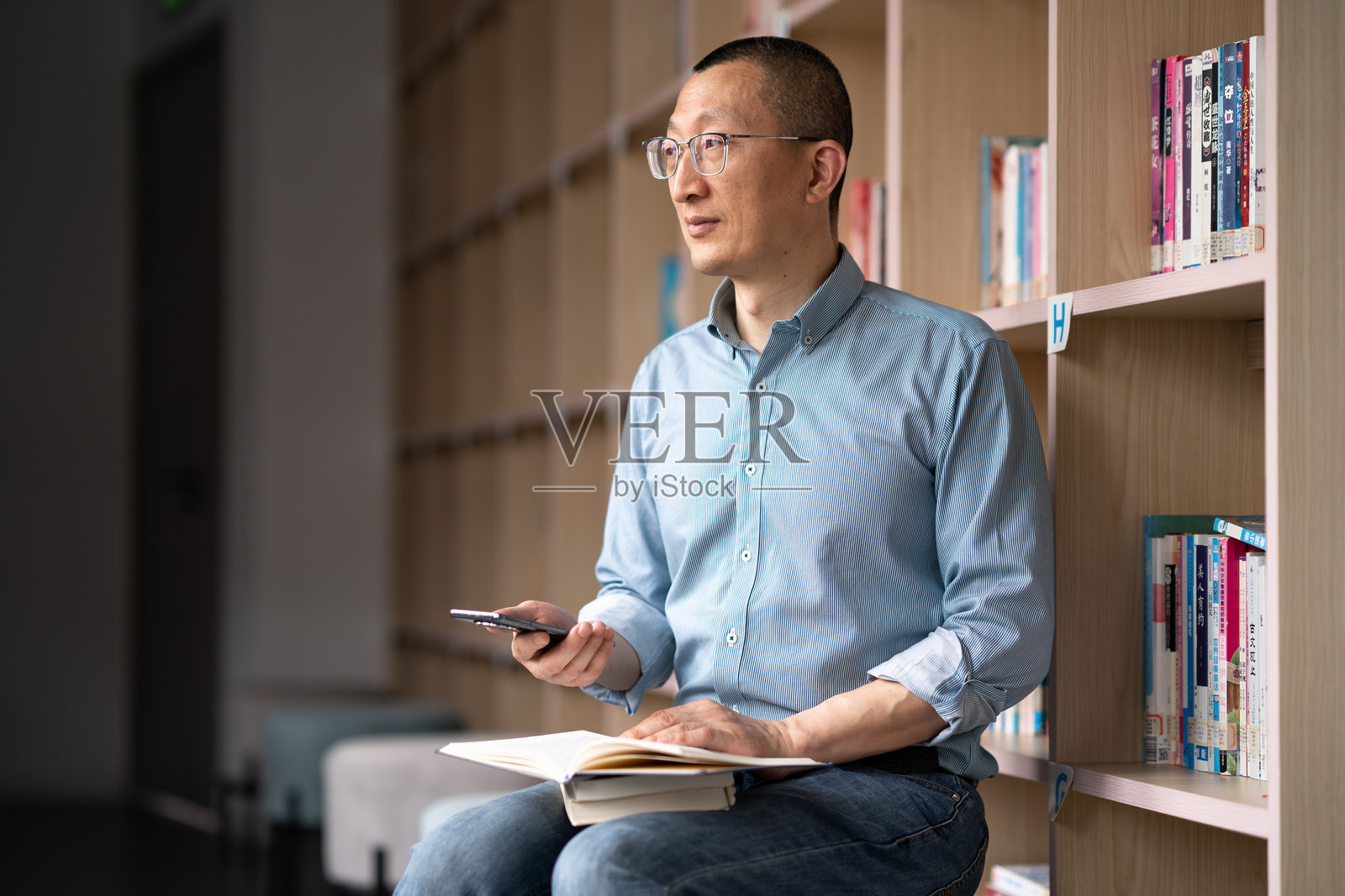 商务人士在书架前看书学习照片摄影图片