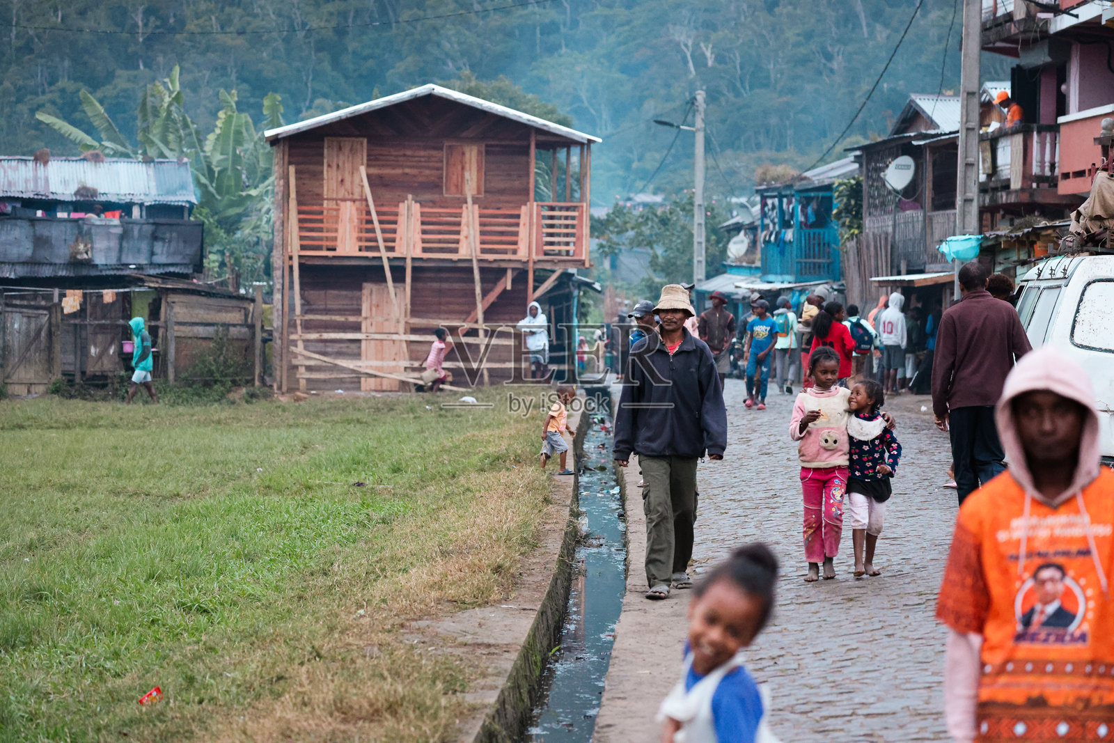探索马达加斯加充满活力的安达西贝村，黄昏时分，当地人沿着鹅卵石街道散步照片摄影图片