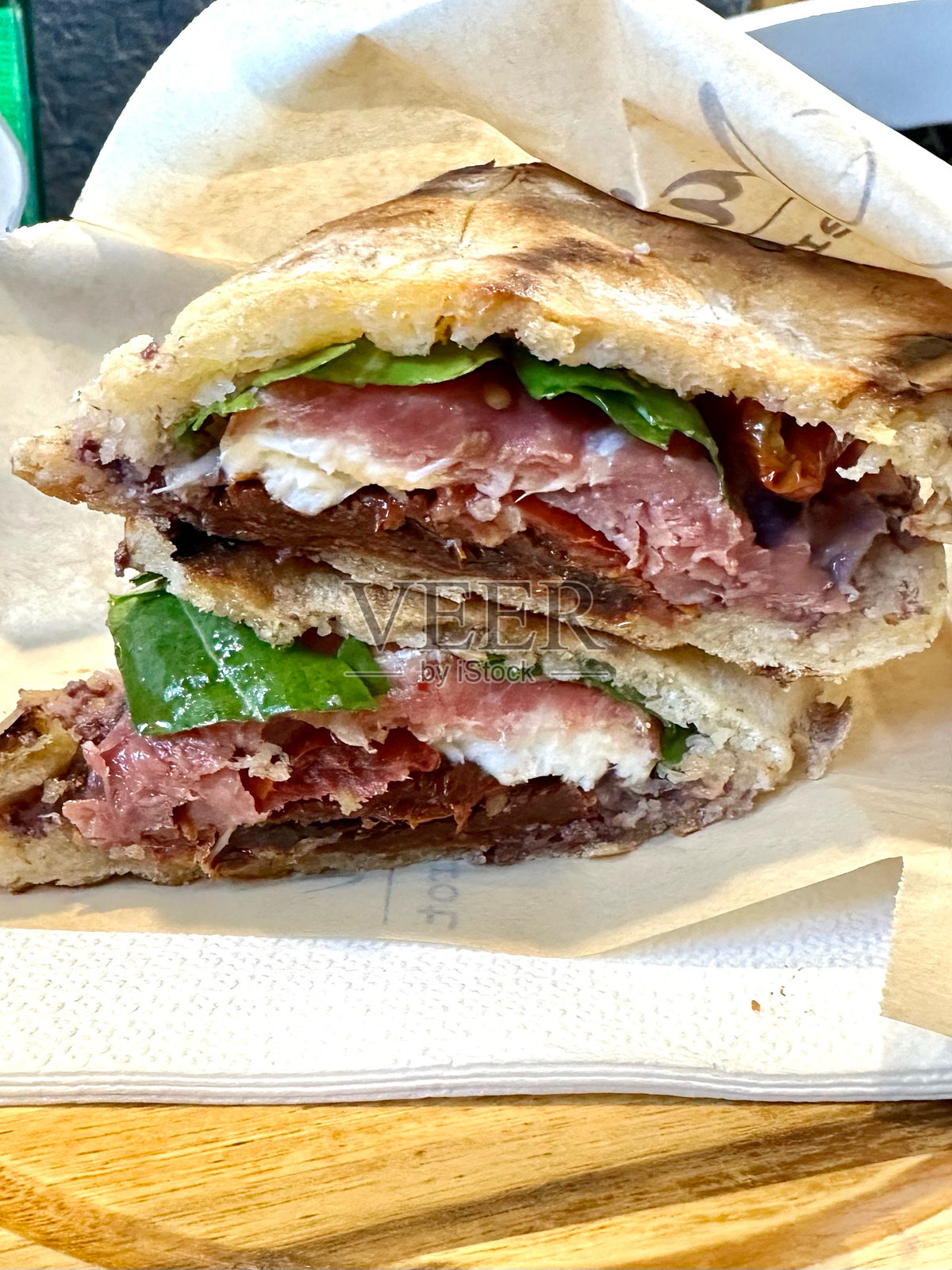 意大利索伦托的一种三明治，里面有熏火腿、马苏里拉奶酪和晒干的西红柿，用熟食纸包裹，然后切成两半照片摄影图片