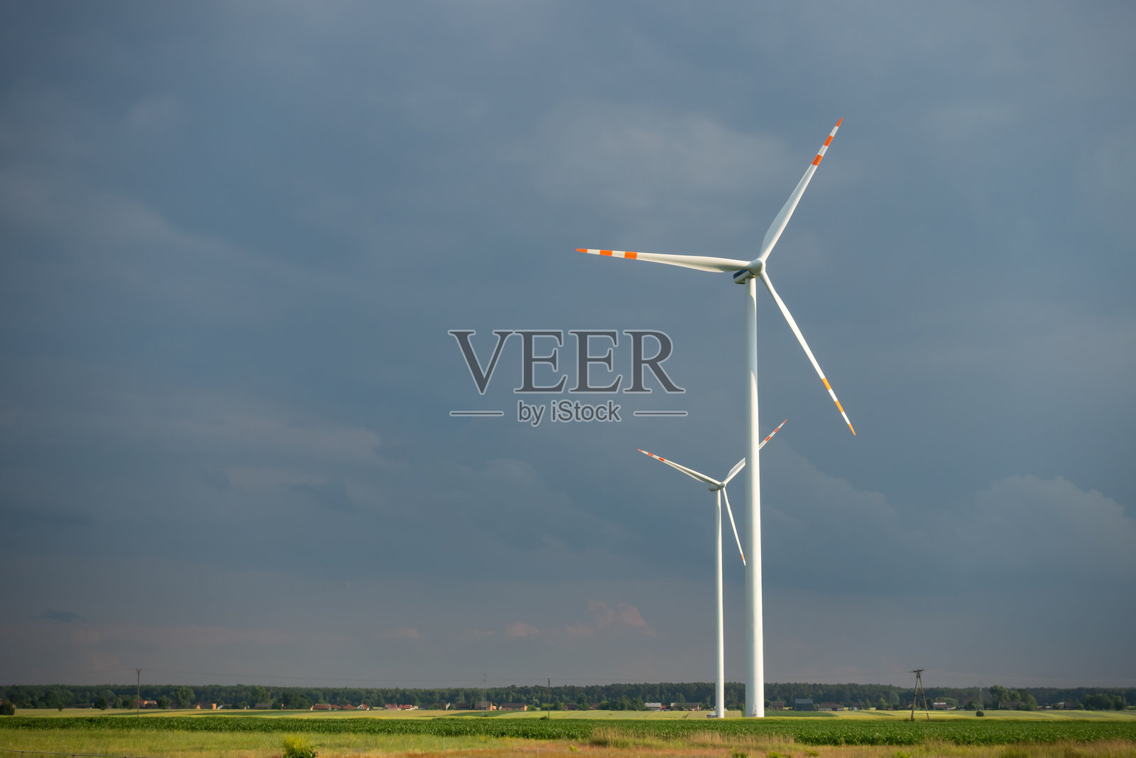 远处白色的风力涡轮机映衬着多云的天空。照片摄影图片